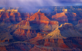 A captivating fine art photograph of the Grand Canyon, captured amidst the drama of a rainstorm. The interplay of light and shadow highlights the canyon's majestic layers, as rain clouds sweep across the landscape, adding a sense of depth and mystique. This image beautifully conveys the raw power and timeless beauty of nature in one of the world's most iconic locations." This description emphasizes the dynamic elements and emotional impact of the scene.