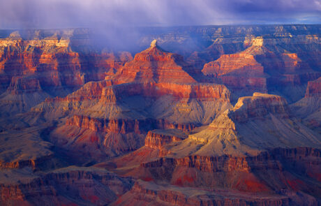 A captivating fine art photograph of the Grand Canyon, captured amidst the drama of a rainstorm. The interplay of light and shadow highlights the canyon's majestic layers, as rain clouds sweep across the landscape, adding a sense of depth and mystique. This image beautifully conveys the raw power and timeless beauty of nature in one of the world's most iconic locations." This description emphasizes the dynamic elements and emotional impact of the scene.