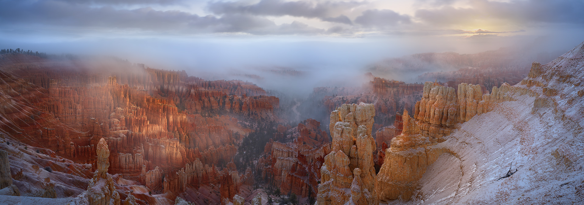 Captured at sunrise in Bryce Canyon National Park, this image came together during a short break in an active snowstorm. Heavy clouds and falling snow had dominated the morning, obscuring the canyon and muting the light. Then, almost unexpectedly, the storm loosened its grip. The clouds lifted just enough to reveal the hoodoos below, while the first light of day filtered through the lingering mist.